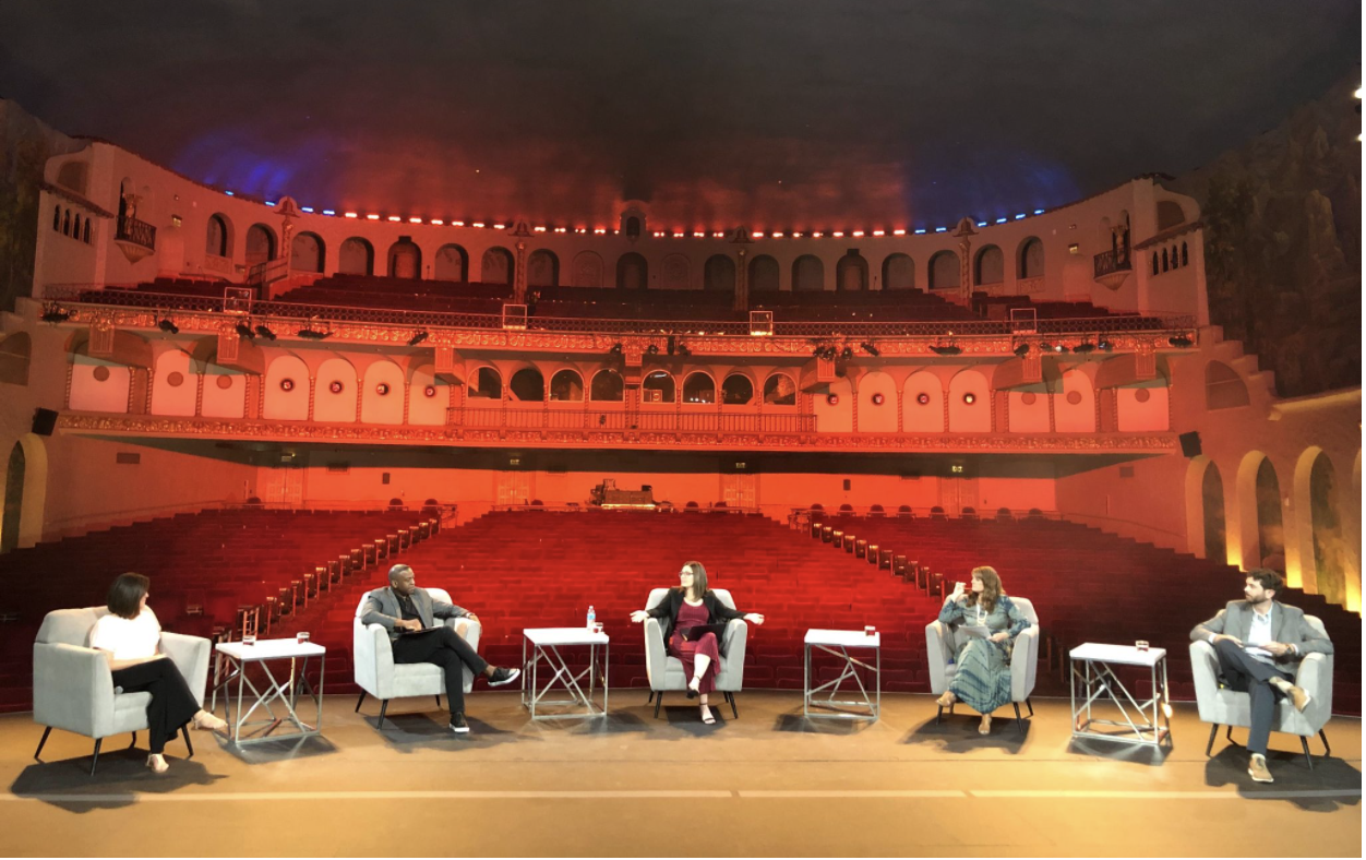 Members of Visit Phoenix sit in socially distanced armchairs on a stage in an empty auditorium.