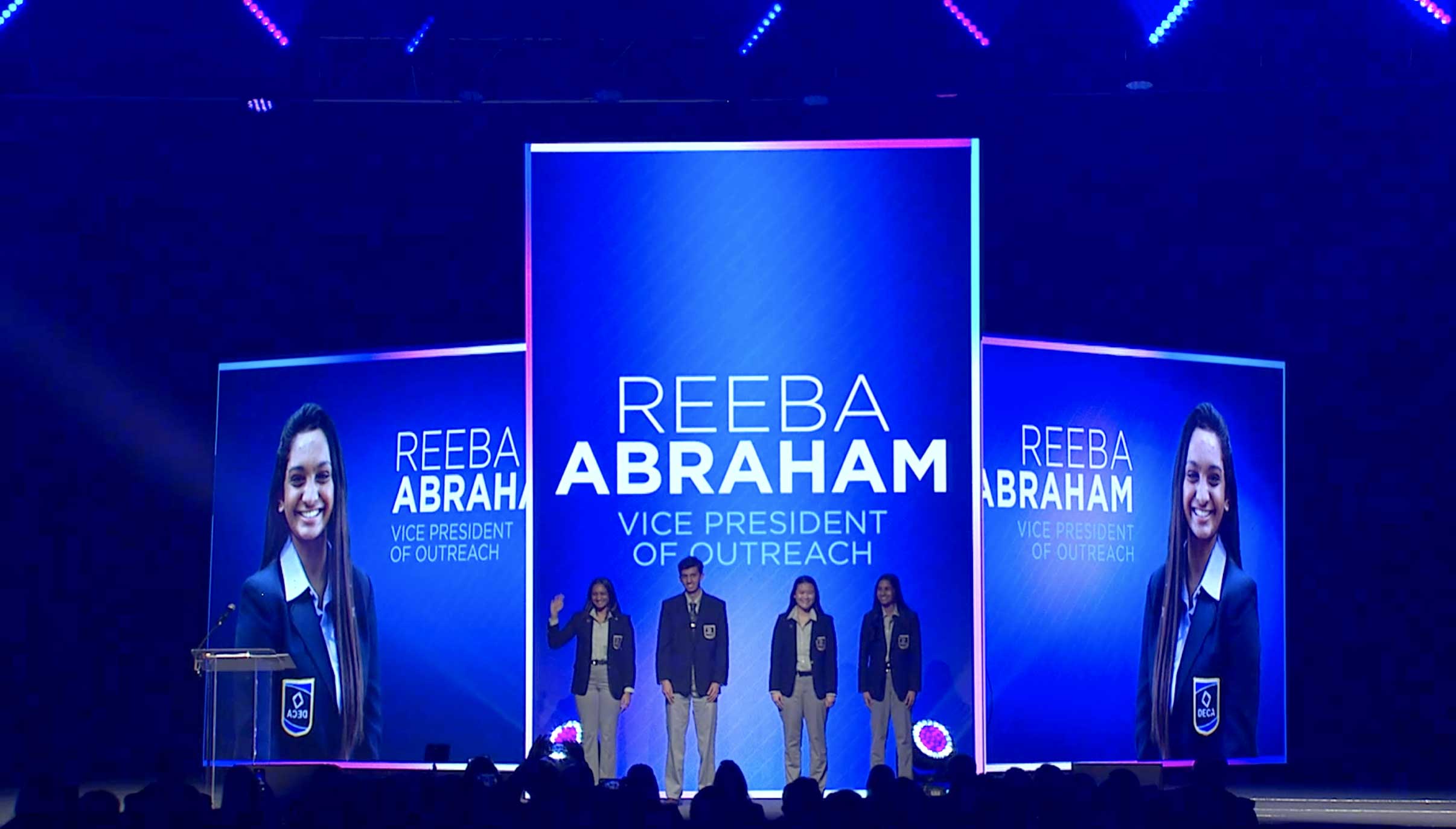 Four officers on stage with photo and name projected in the background.